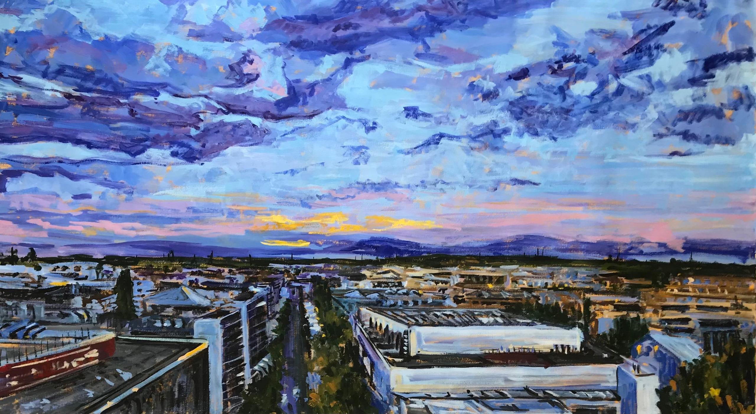 Polígono industrial con naves y edificios en primer plano. Al fondo en el horizonte la sierra y la puesta de sol amarilla y azul.