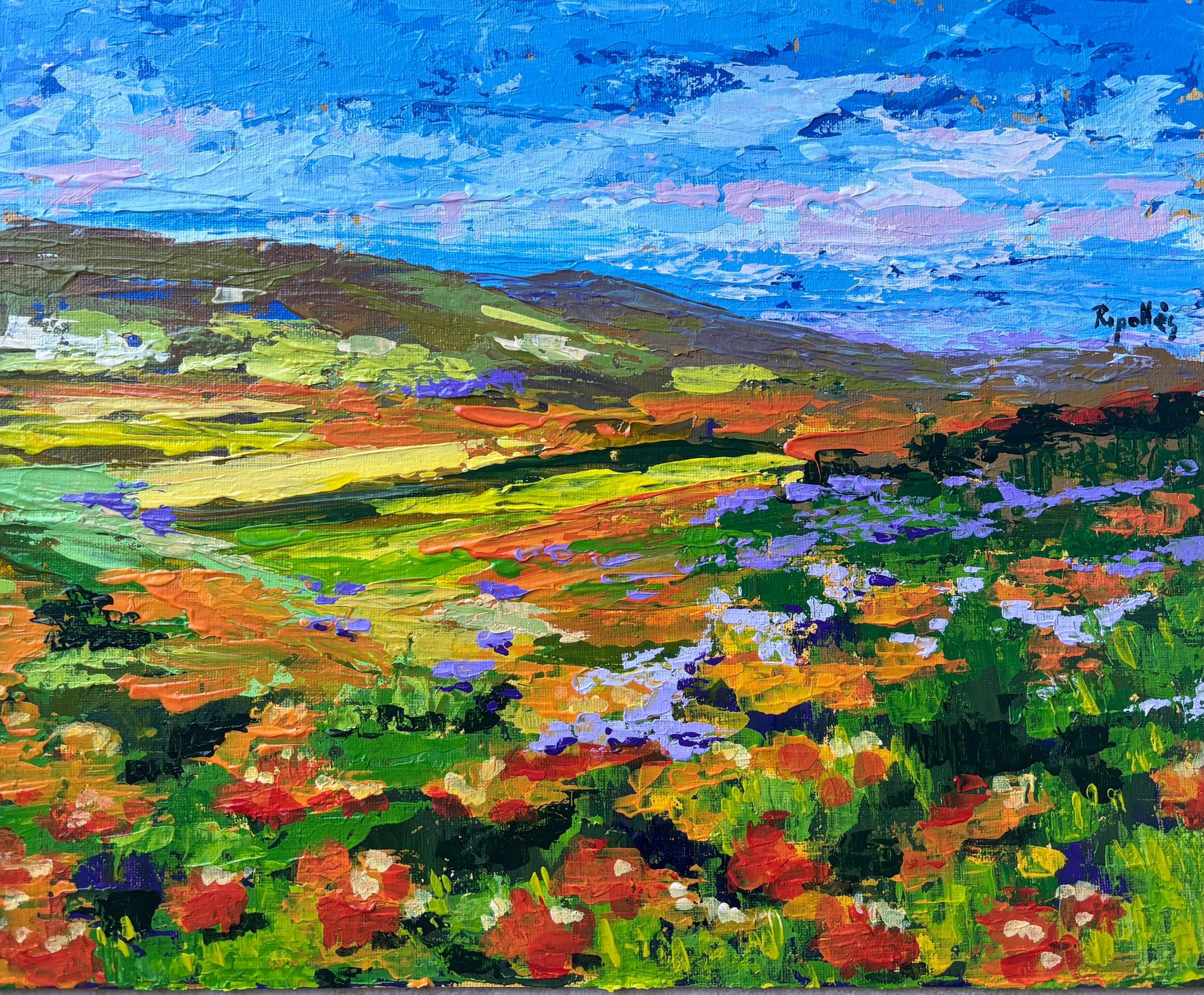 Paisaje de un campo con flores salvajes naranjas y lilas en primer plano. Colinas en el horizonte que dan paso a un cielo azul brillante.